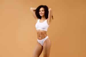 A woman posing in white underwear showing the results of a body contouring procedure