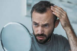 Mature man examining hair loss in the mirror