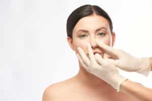 Plastic surgeon examining a woman’s nose before rhinoplasty.