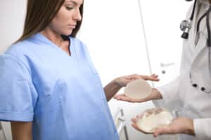 Woman looking at two different types of implants to decide what she wants in revision.