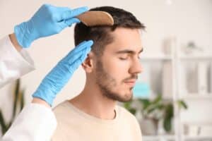 Doctor running comb through man's hair after successful Neograft hair restoration treatment.
